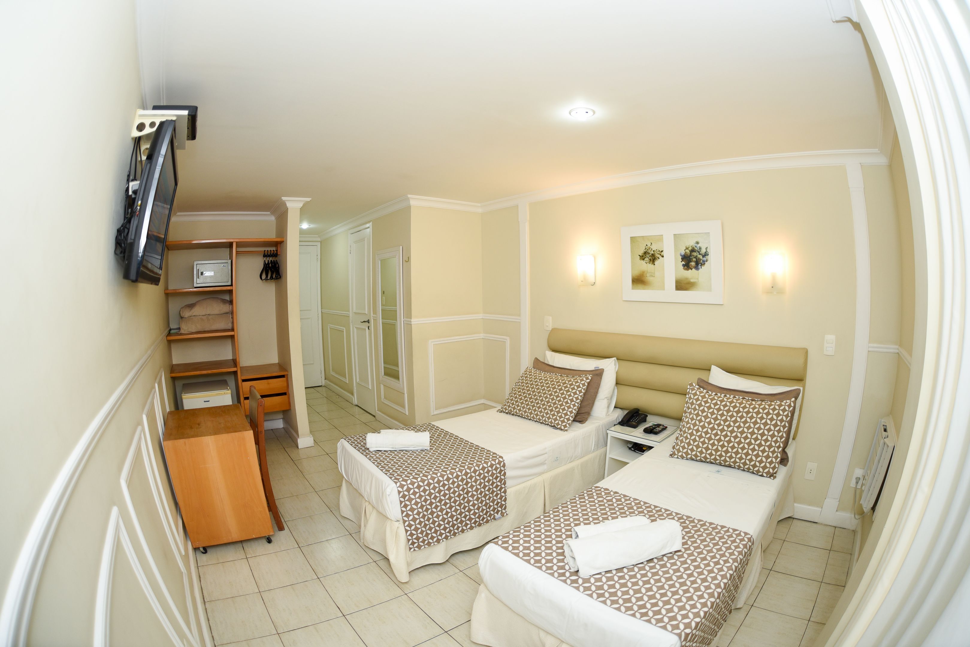 Hotelkamer met twee bedden, een bureau, een stoel, een televisie en een kledingkast.