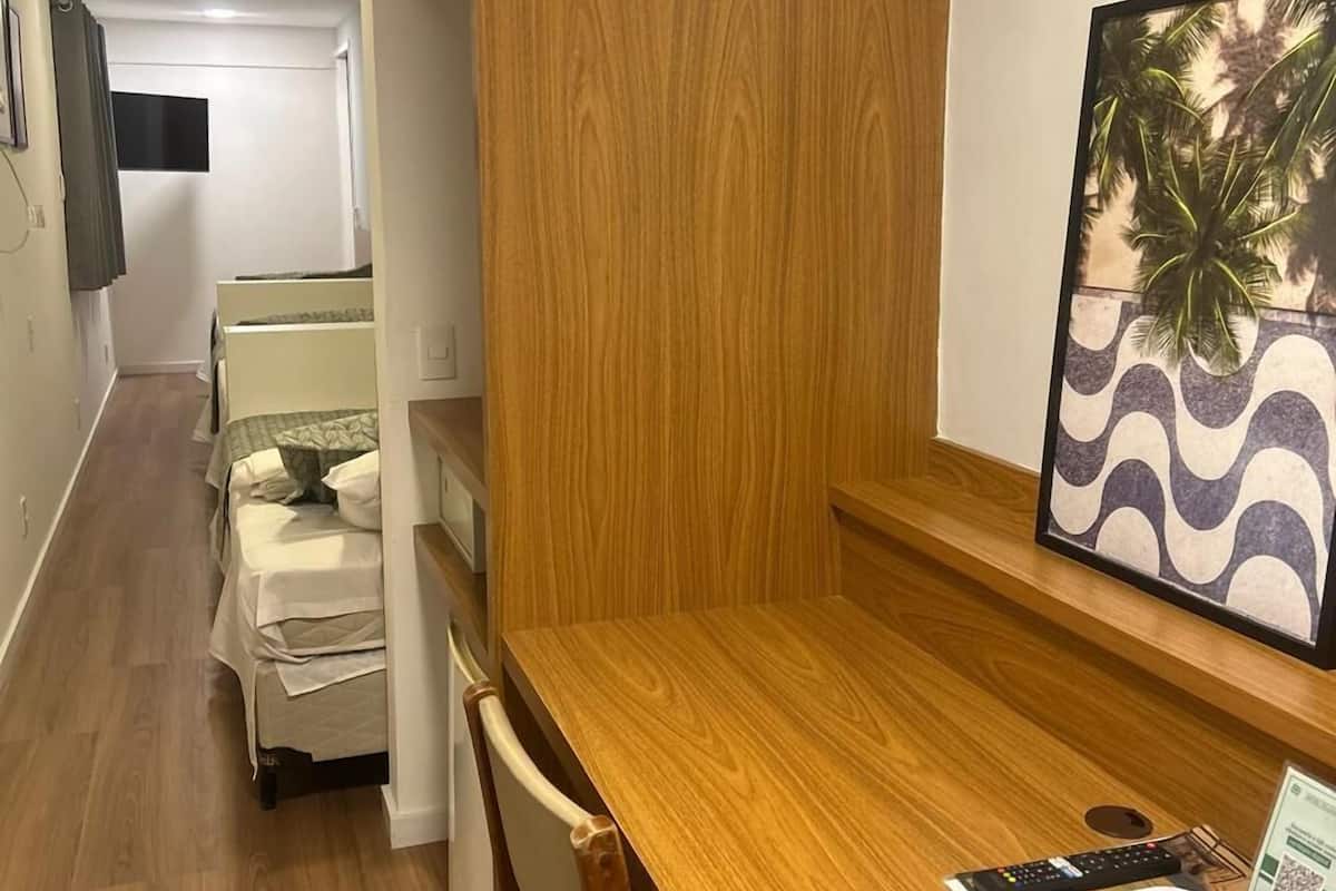 Een houten eettafel met stoelen, een lijst met een afbeelding van palmbomen en een kleine tafellamp.