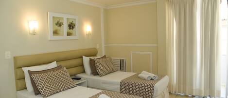 A hotel room with two beds, a table, and a chair.