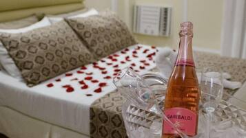 Un dormitorio con una cama, una mesita de noche con una botella de vino y una copa.