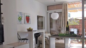 A modern, well-lit room with a dining area, a sofa, and a large window with curtains. - Apartments Ljiljana (Zadar)