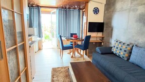 A modern living room with a sofa, a coffee table, and a dining area with chairs and a table. - Apartments Ljiljana (Zadar)