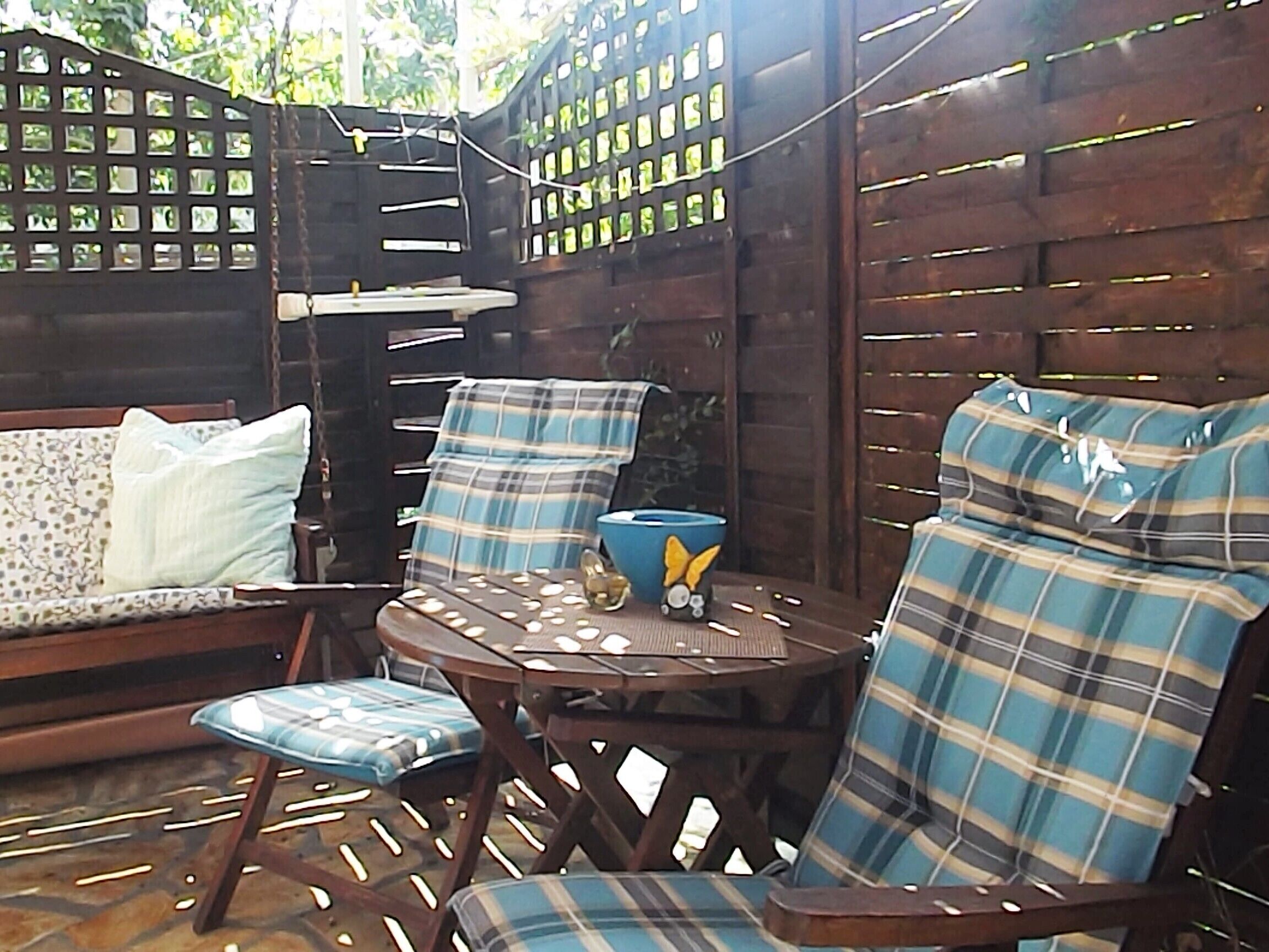 An outdoor seating area with a wooden table and chairs, a blue bowl, and a decorative item on the table.