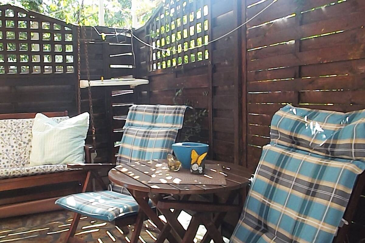 An outdoor seating area with a wooden table and chairs, a blue bowl, and a decorative item on the table.