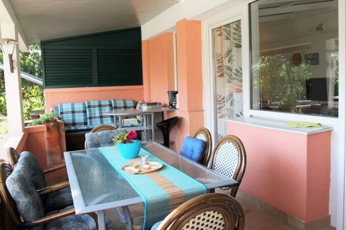 A dining area with a table set for two, surrounded by wicker chairs.