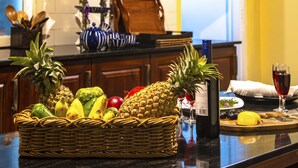 Een keuken met houten kastjes, een mand met fruit en een wijnglas op het aanrecht.