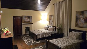 Una camera d'albergo con un letto, un comodino, una lampada, una sedia, un camino e due quadri.