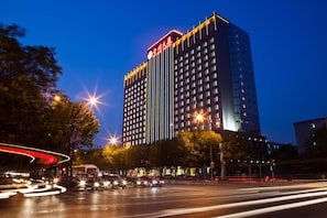 A high-rise hotel with a prominent sign at the top, multiple floors, and a busy intersection in the foreground with light trails from moving vehicles. - Beijing Guizhou Hotel  (Beijing)