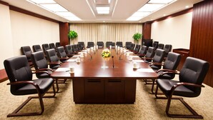 Uma sala de conferências com uma mesa comprida, várias cadeiras e um projetor no teto.