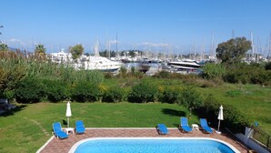 A swimming pool with lounge chairs and a view of a marina with boats. - Corfu Anastasia (Corfu)