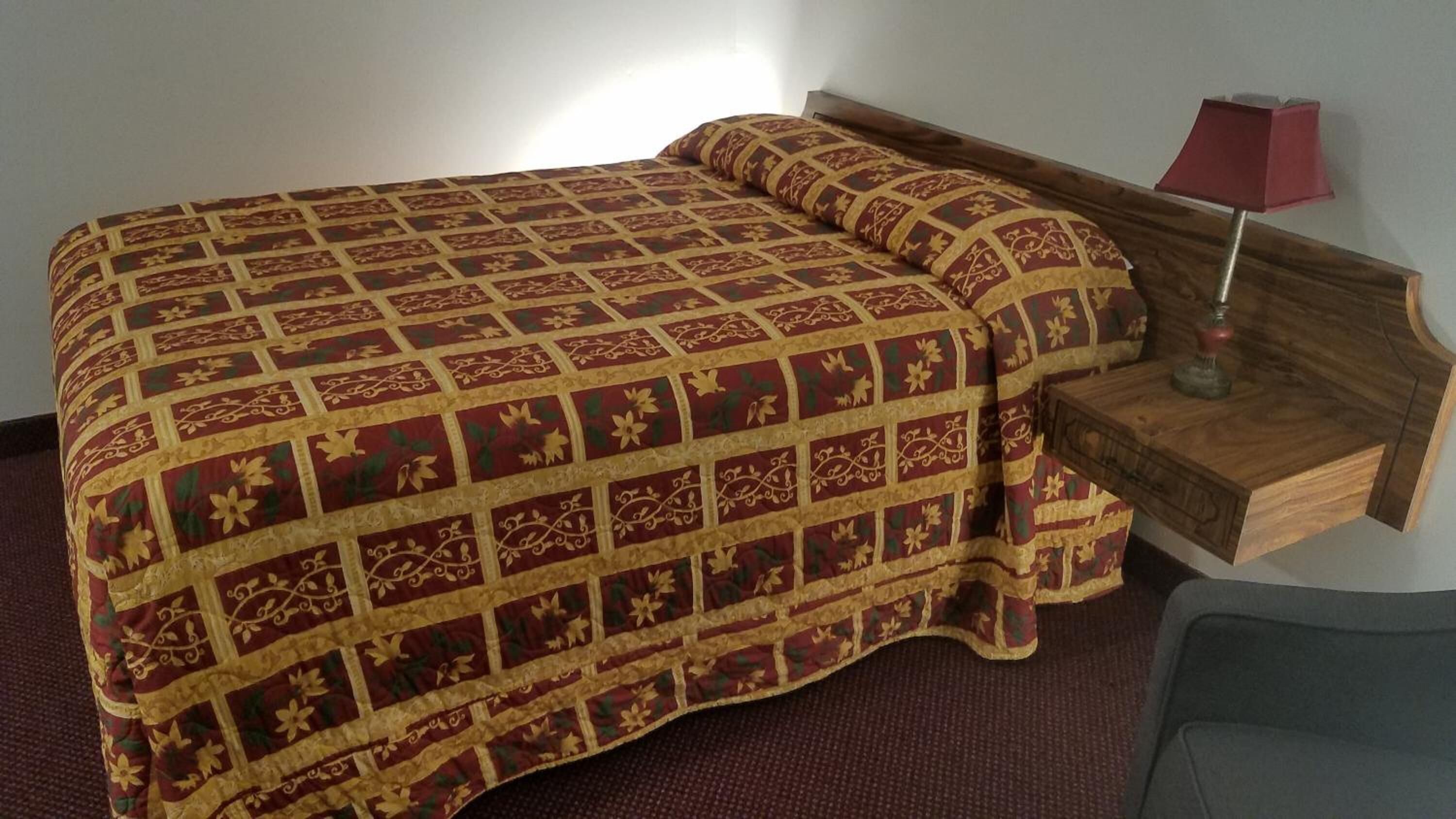 Une chambre d’hôtel avec un grand lit, une table de chevet en bois avec une lampe et une chaise.