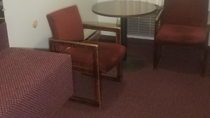 A room with a round table, two armchairs, and a patterned sofa. - Amber Inn Motel (Bliss)