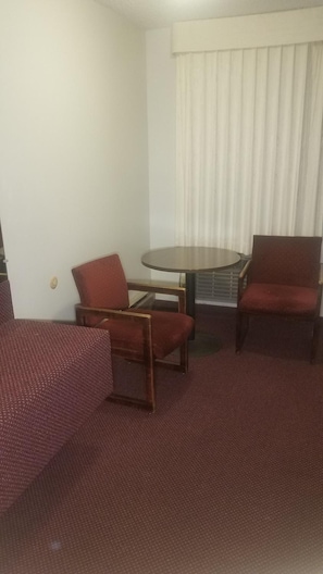 Um quarto com uma mesa redonda, duas poltronas e um sofá estampado.