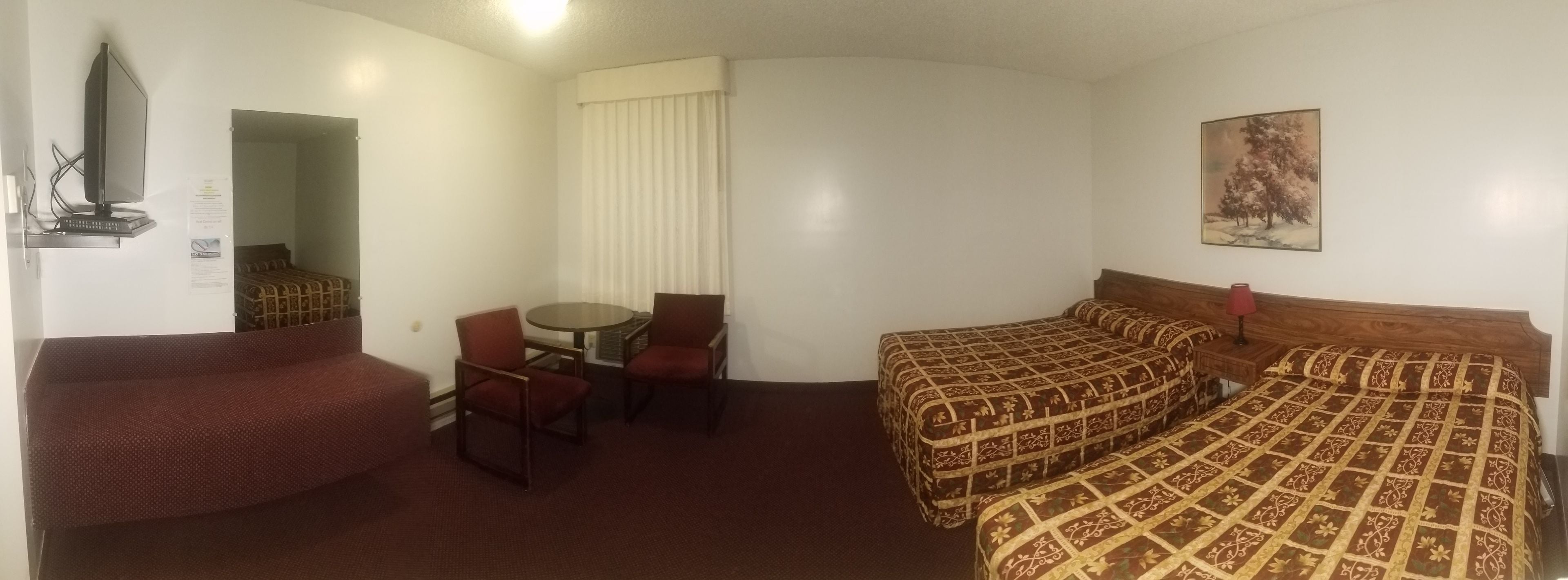 A hotel room with a bed, a chair, a small table, and a mirror.