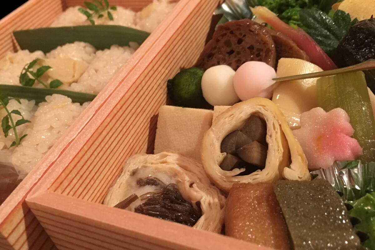 Una caja bento con diferentes alimentos, como arroz, verduras y vegetales encurtidos.