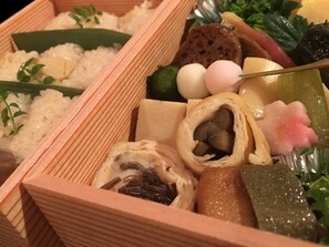 Una caja bento con diferentes alimentos, como arroz, verduras y vegetales encurtidos.