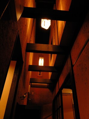 A narrow, dimly lit corridor with wooden beams and a small window at the end. - Theatre and Library Residence -Kyoto Murasakino- (Kyoto)