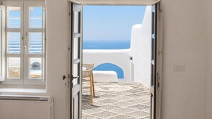 Una puerta que da a un balcón con vistas al mar, un suelo con diseño y una pared blanca.
