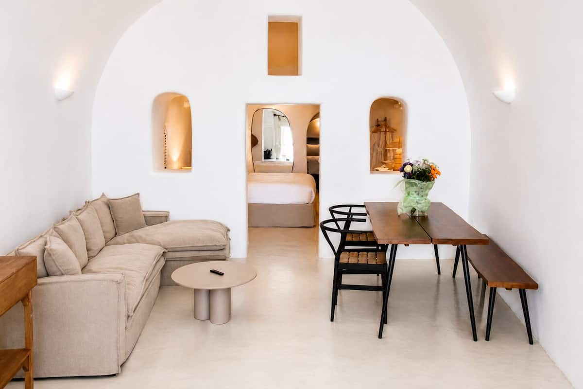 Un espacio habitable moderno y minimalista con un sofá, una mesa redonda y una mesa de comedor.