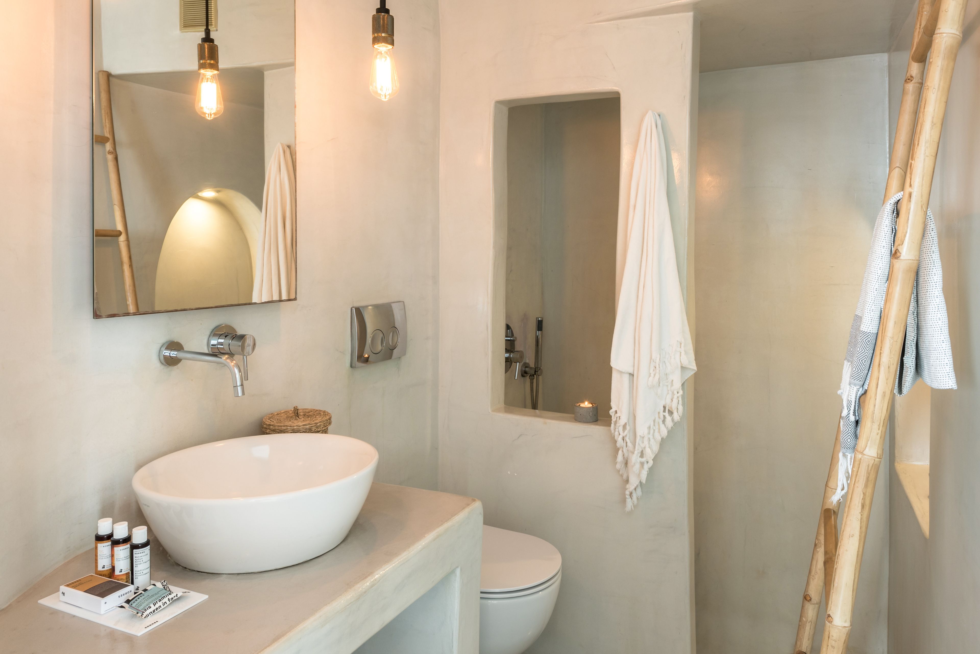Une salle de bain avec un grand lavabo blanc, un miroir, un porte-serviettes et un espace douche.