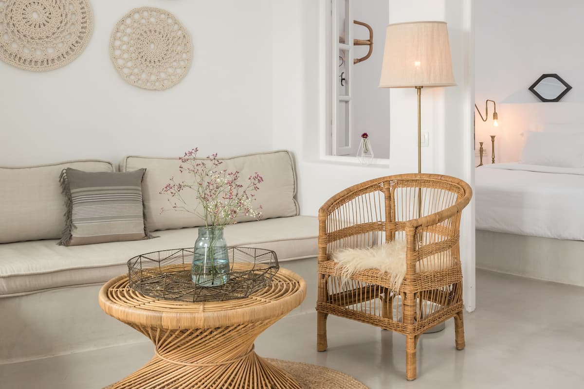 Una sala de estar moderna con un sofá, una silla de mimbre, una mesa redonda de centro y arte decorativo en la pared.