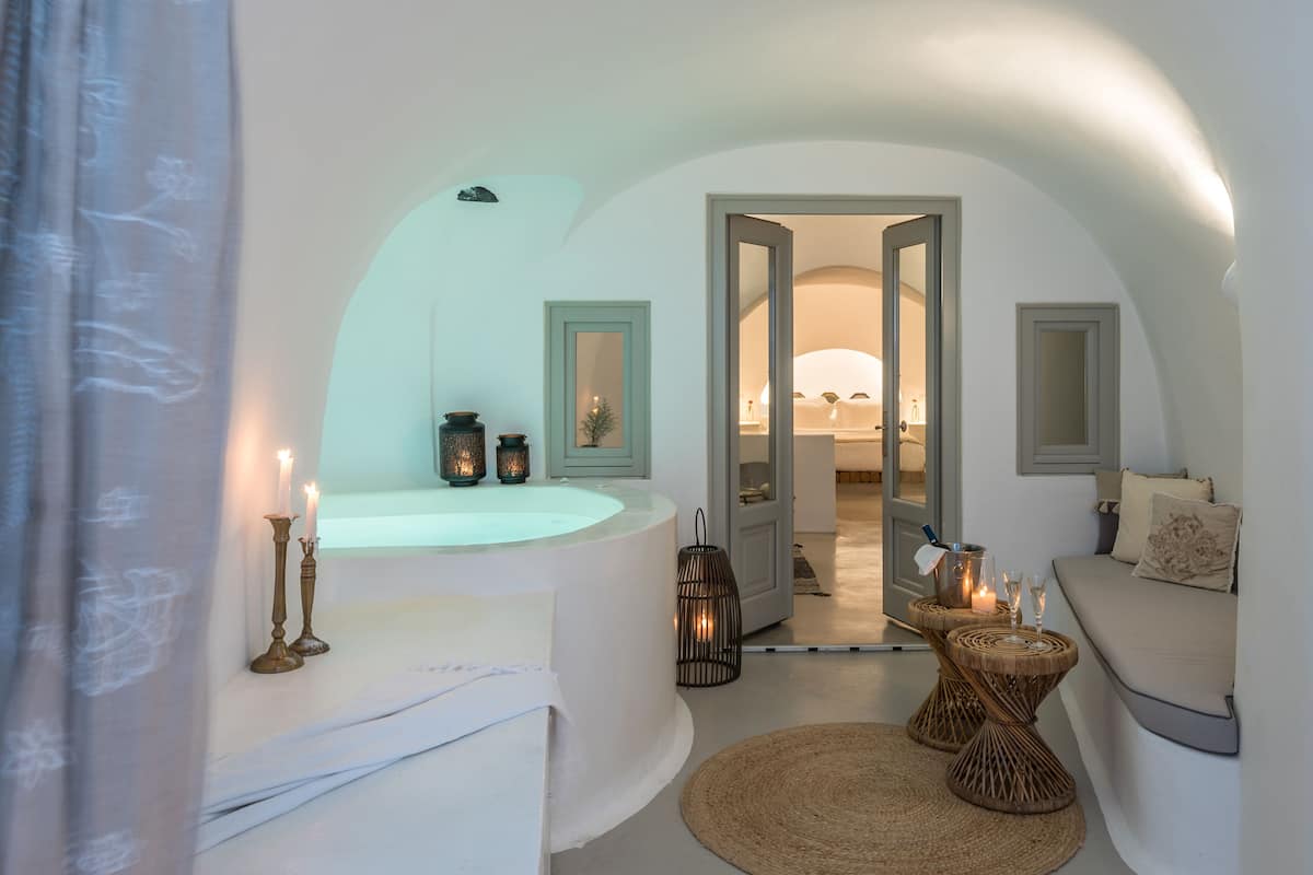 Una habitación con techo curvo, una bañera, una mesita de mimbre y un taburete de mimbre.