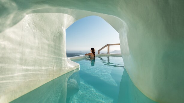 Una persona en una piscina cristalina con vista al cielo y al paisaje distante.
