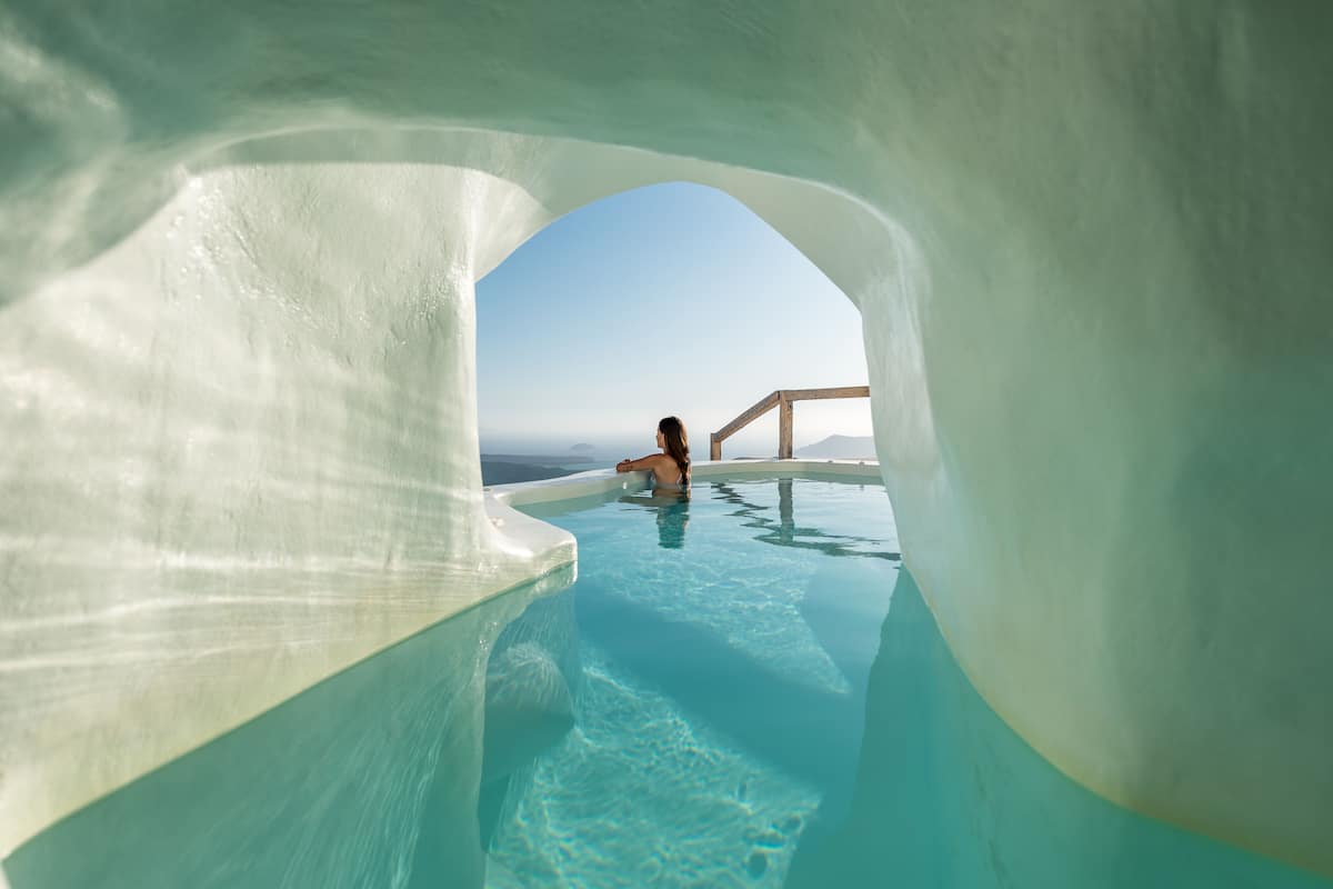 Una persona en una piscina cristalina con vista al cielo y al paisaje distante.