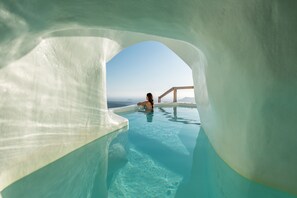 Eine Person in einem klaren Pool mit Blick auf den Himmel und die ferne Landschaft.