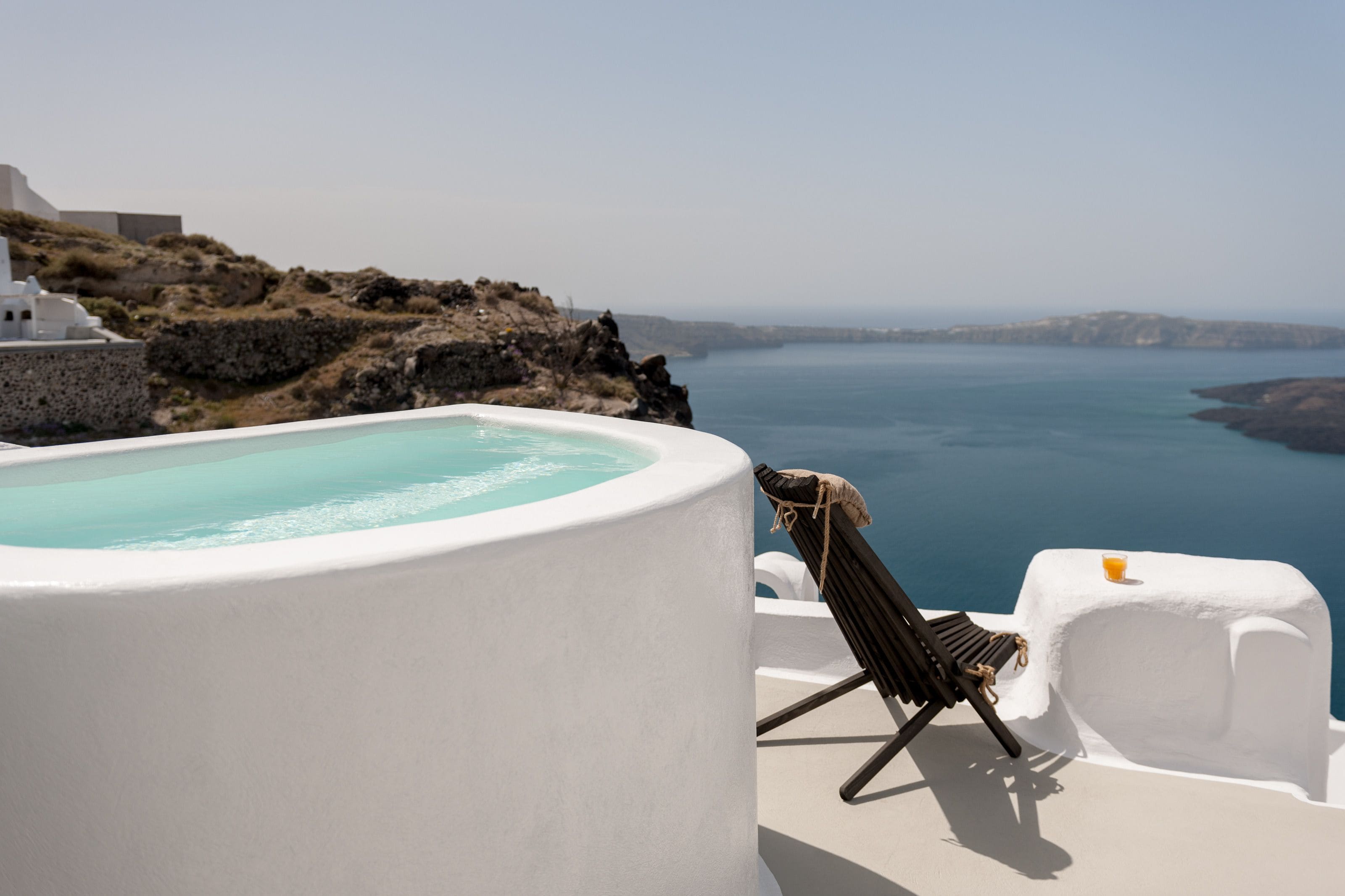 Una piscina infinita blanca con vista despejada al mar y un paisaje rocoso.