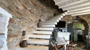A stone-walled interior with a staircase leading to a kitchen area. - The Stone Windmill (Kea)