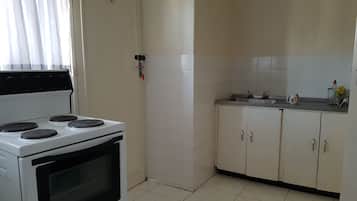 A kitchen with a stove, cabinets, and a sink.