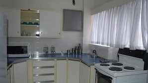 A compact kitchen with a microwave, stove, and various kitchen appliances. - Lolos Elegant Three Bedroom Apartment (Harare)