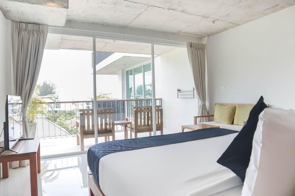 Une chambre d’hôtel avec un lit, un bureau et un balcon équipé de chaises.