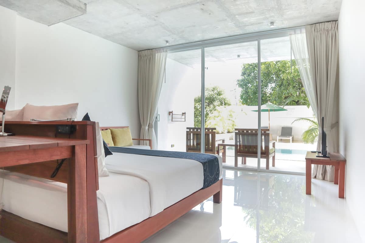 Une chambre moderne avec un lit, une table de chevet et une vue sur un espace piscine extérieur.