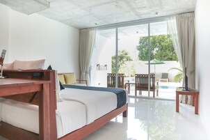 A modern bedroom with a bed, bedside table, and a view of an outdoor pool area.