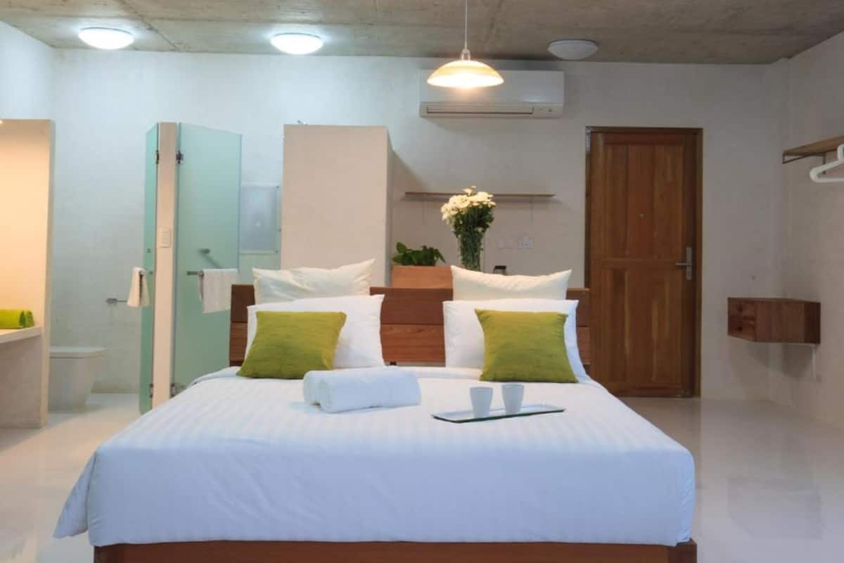 Une chambre à coucher bien rangée, avec un lit, une table de chevet et un luminaire suspendu.