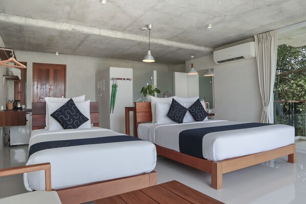 A modern hotel room with two beds, wooden headboards, a small desk, and a balcony with a view.