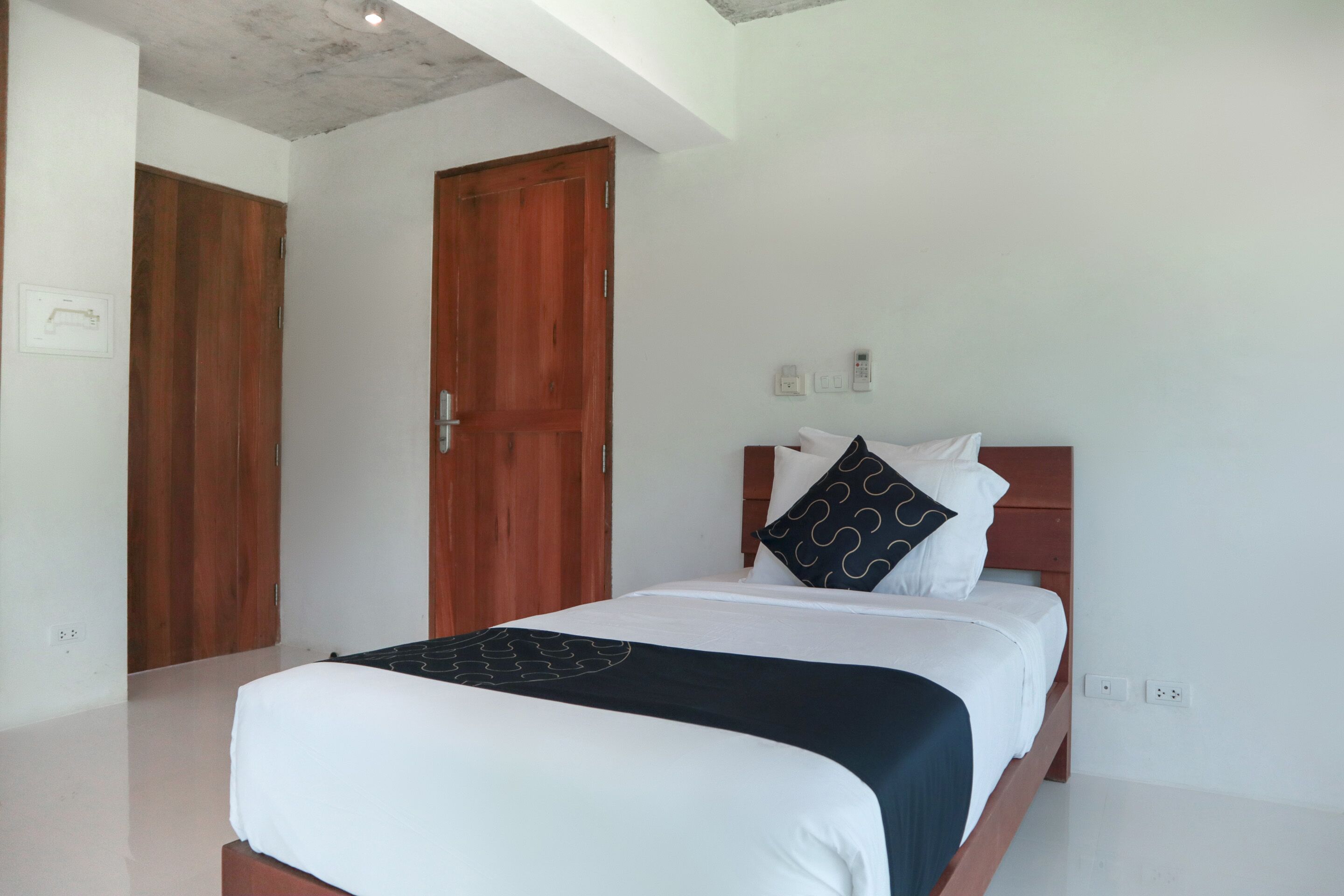 A bedroom with a bed, wooden wardrobe, and a white wall.