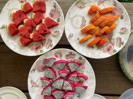 Three plates with watermelon, carrot sticks, and dragon fruit slices on a wooden table.
