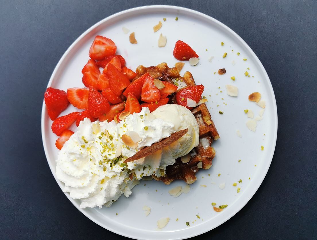 A plate with waffles, strawberries, and whipped cream.