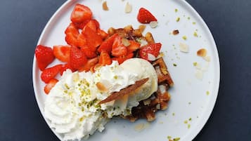 A plate with waffles, strawberries, and whipped cream.