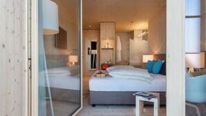 A modern hotel room with a large bed, a small table, and a glass partition. - Bever Lodge (Bever)