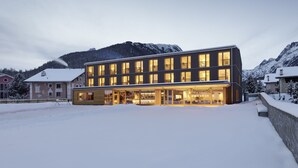 A modern hotel with multiple floors, large windows, and a snow-covered landscape in the background. - Bever Lodge (Bever)