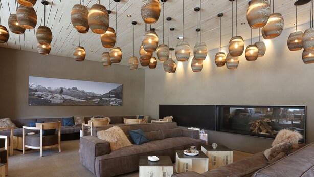 A modern living room with a sectional sofa, a flat-screen TV, and decorative hanging lights. - Bever Lodge (Bever)