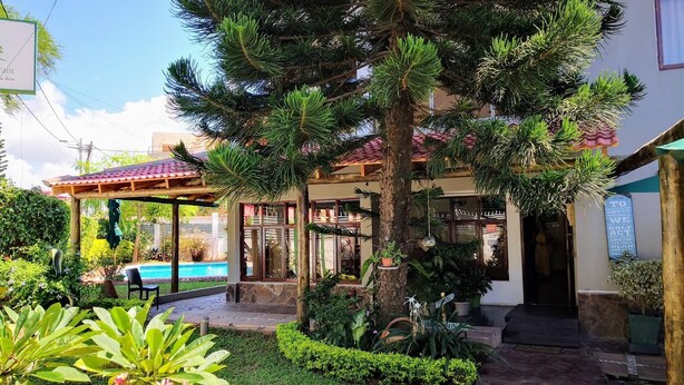 A building with a covered patio, a swimming pool, and various potted plants. - Sommerschield Guest House & Restaurant (Maputo)