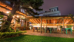 An outdoor patio area with tables and chairs, surrounded by greenery and a building in the background. - Sommerschield Guest House & Restaurant (Maputo)