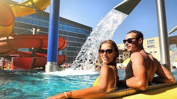 Zona de piscina con toboganes de agua y un edificio moderno al fondo.