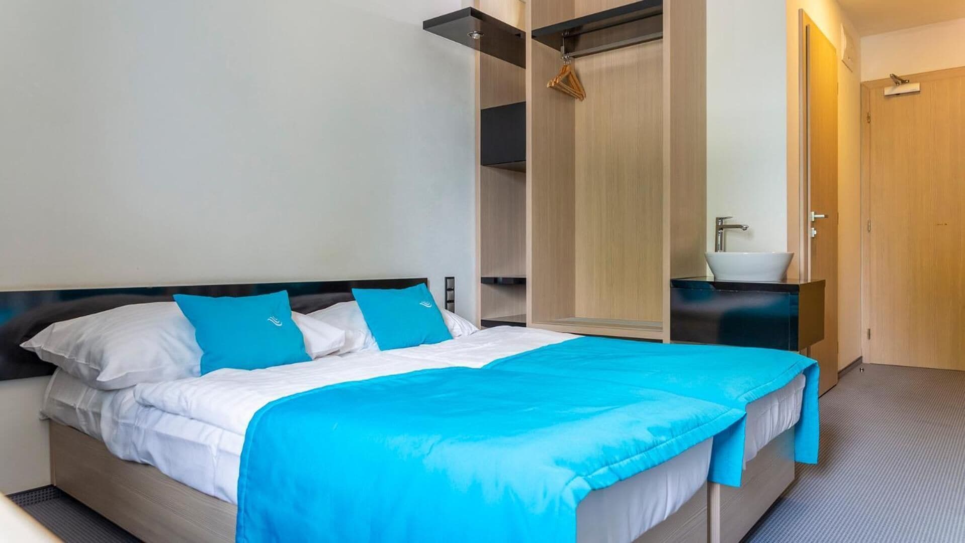 A modern hotel room with a bed, a wardrobe, and a bathroom.