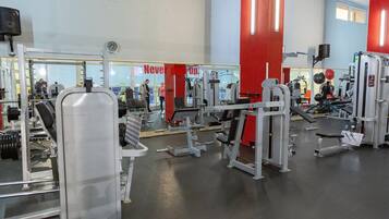 A gym with various exercise equipment, a clock on the wall, and a motivational sign.